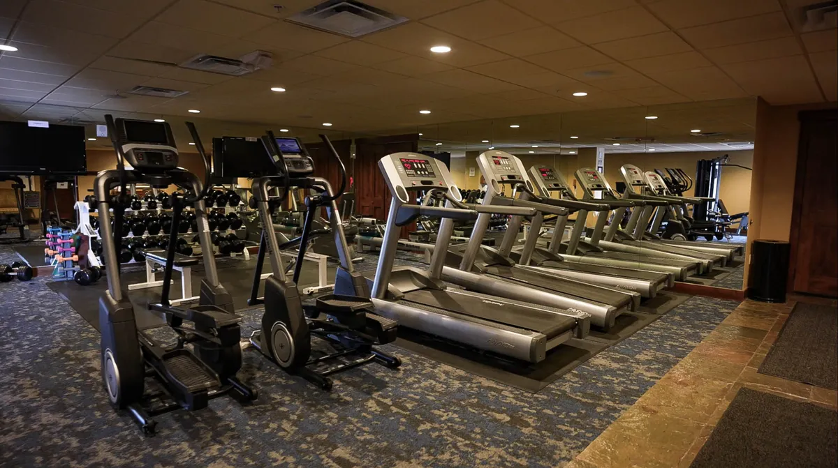 This interior shot captures a well-equipped fitness center with elliptical machines, treadmills, dumbbells, and mirrors. The space is bright and modern, inviting guests to work on their fitness goals even while away from home.
