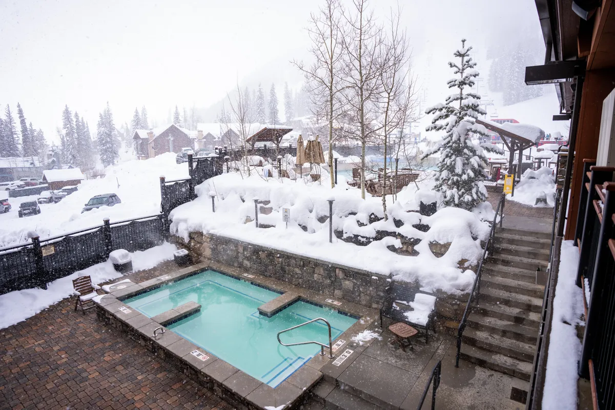 This image features a steaming outdoor hot tub set against a snowy landscape and surrounded by trees. The relaxation and sense of exclusive retreat are evident, with the hot tub positioned as a prime spot to unwind and enjoy winter scenery.