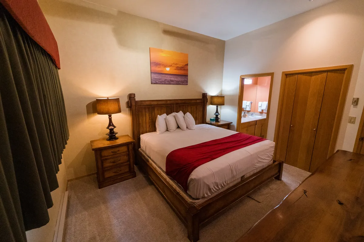A tranquil bedroom scene with a neatly made bed, soft lighting from table lamps, and soothing artwork on the wall. The space is designed for comfort and quiet, ideal for restful nights and peaceful mornings.